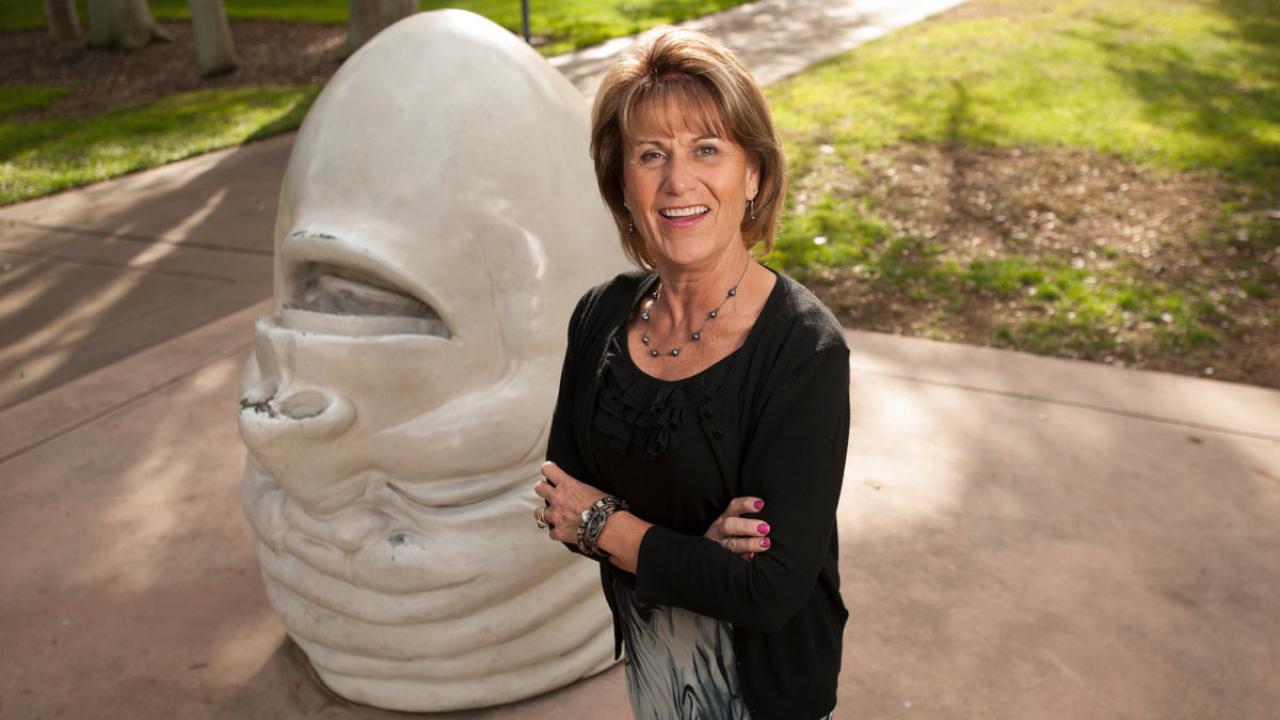 Woman poses with "Eye on Mrak" Egghead sculpture.