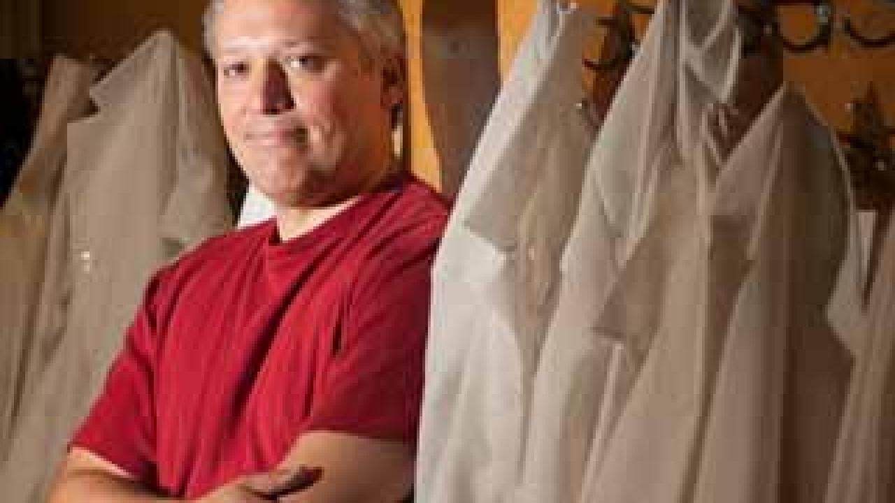 Man standing a rack of lab coats