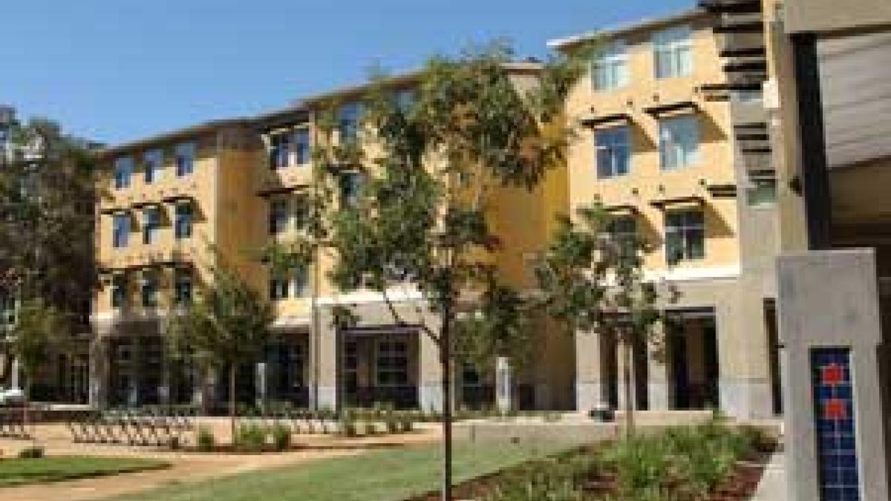 Photo: four-story building with trees and garden in foreground