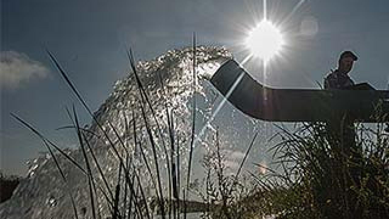 Water flows from a large pipe as a man monitors the well flow rate