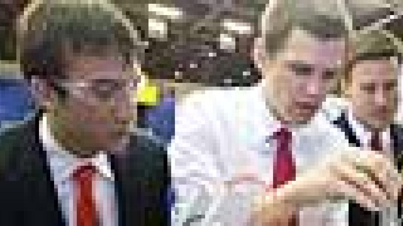 Three guys with the middle man gesturing and the other two watching