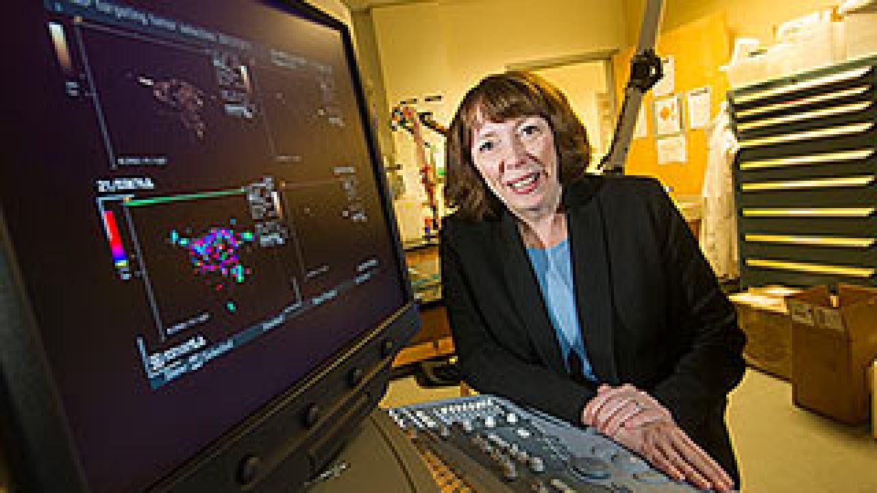 Woman posing near a computer that has images on it