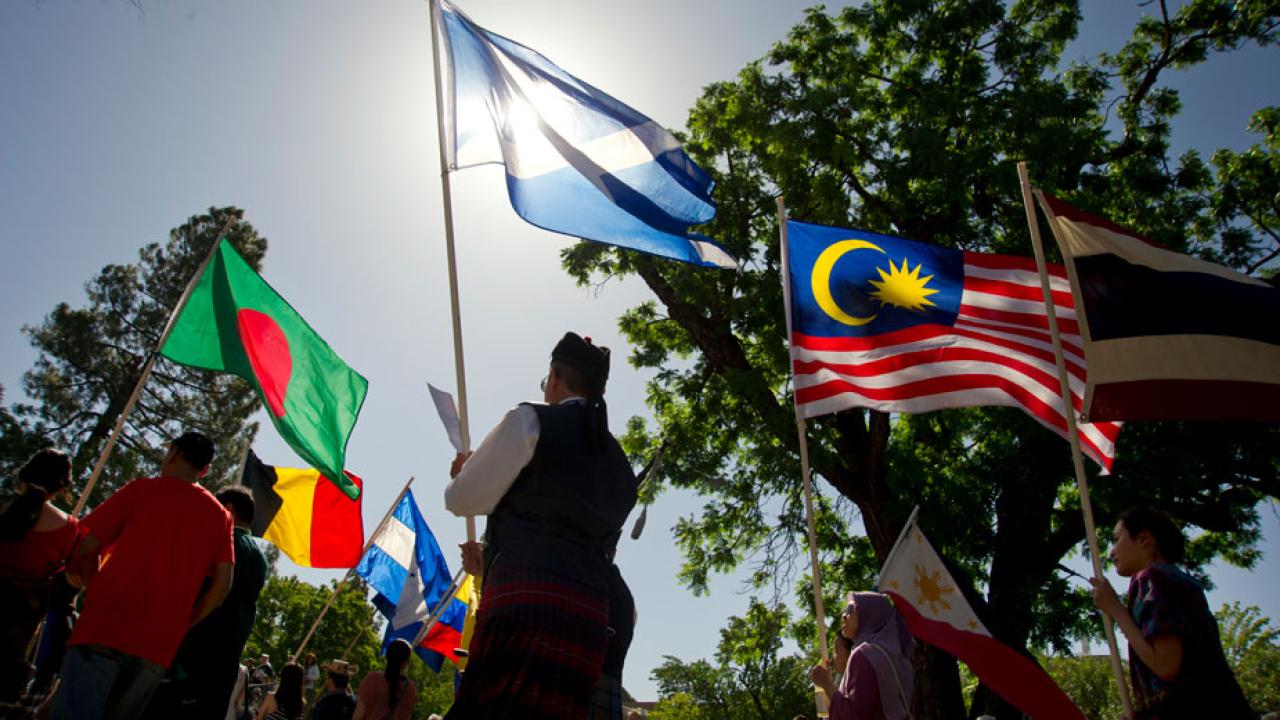 Parade participants carry flags of various nations.