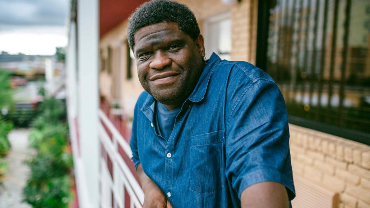 Gary Younge on balcony, environmental portrait