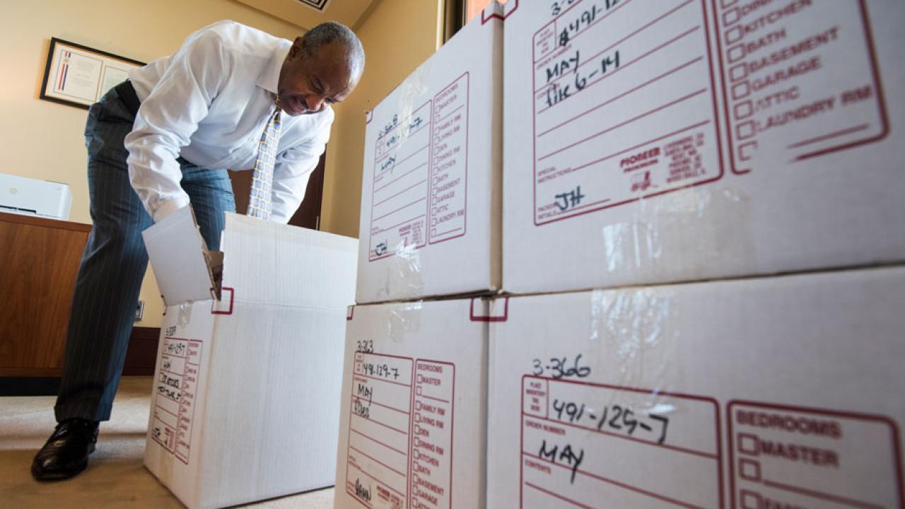 Chancellor Gary S. May unpacks a box in his office.
