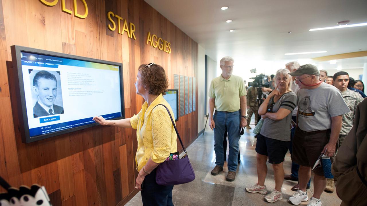 People look at a TV screen displaying the Golden Memory Book.