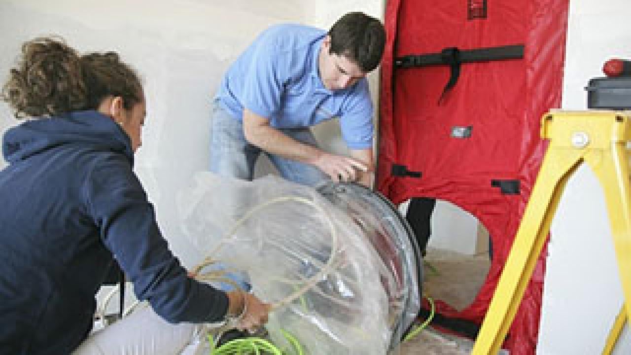 Woman and man working on equipment next to sealed door