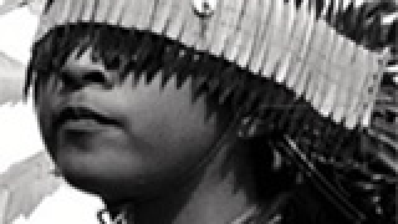 photo: Indian boy in headdress covering his eyes