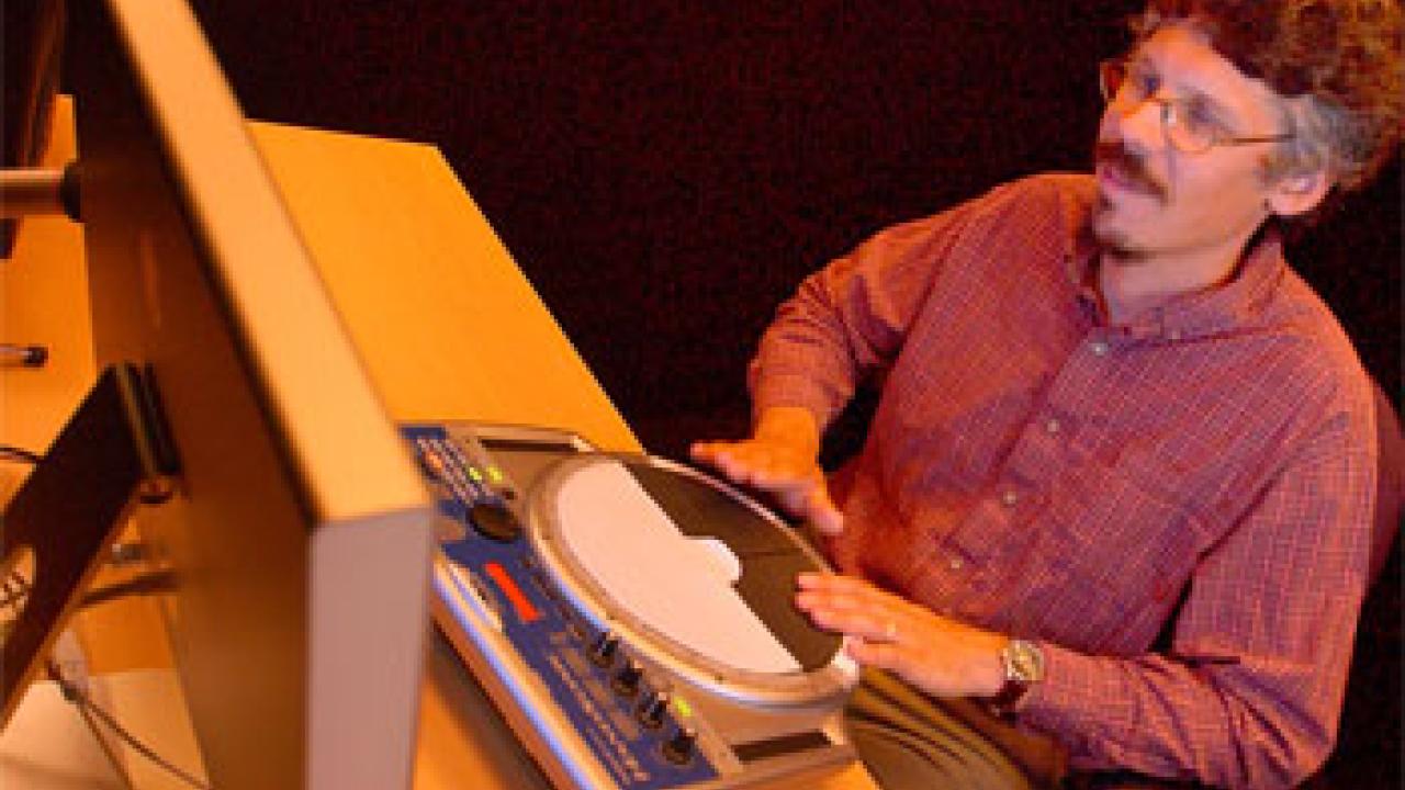 photo: man at computerized drum machine in front of a computer