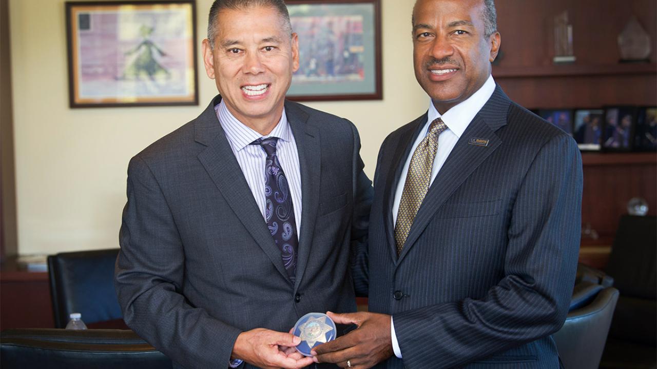 Joe Farrow and Gary S. May hold a police badge.