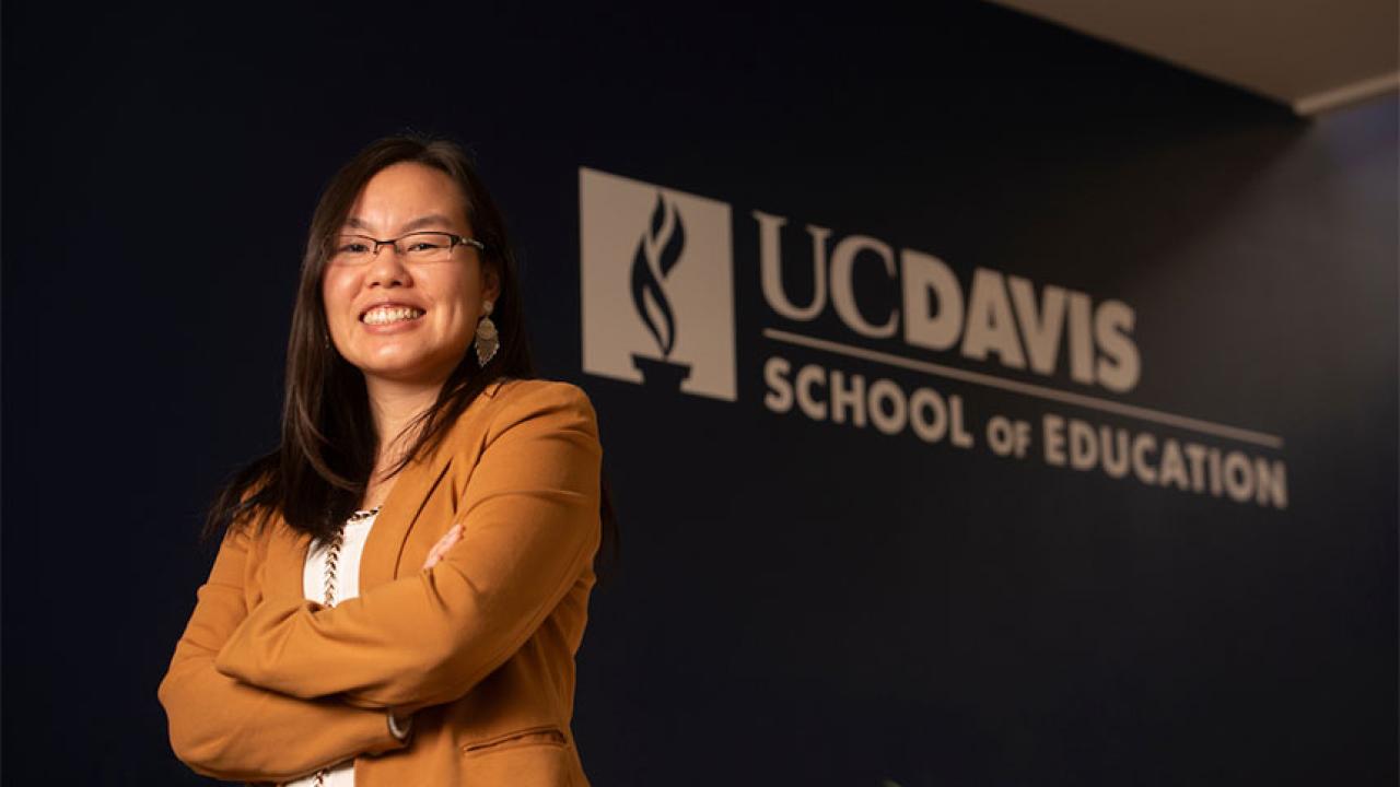 A woman poses in front of a School of Education sign