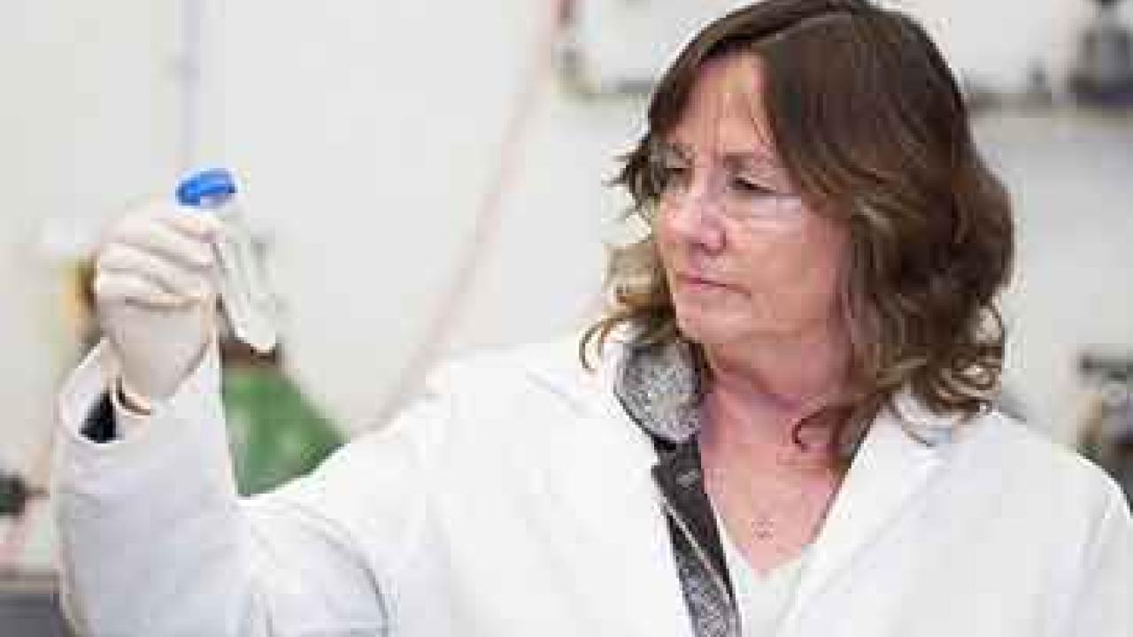Woman in lab coat looking at a test tube