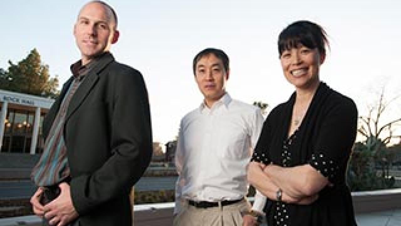 Two men and a woman posing in front of Rock Hall
