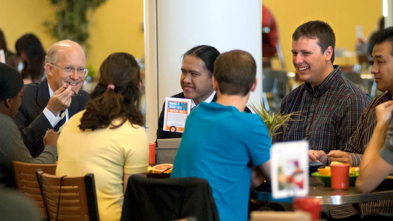 Ken Burtis chates with a table full of students in the Dining Commons.