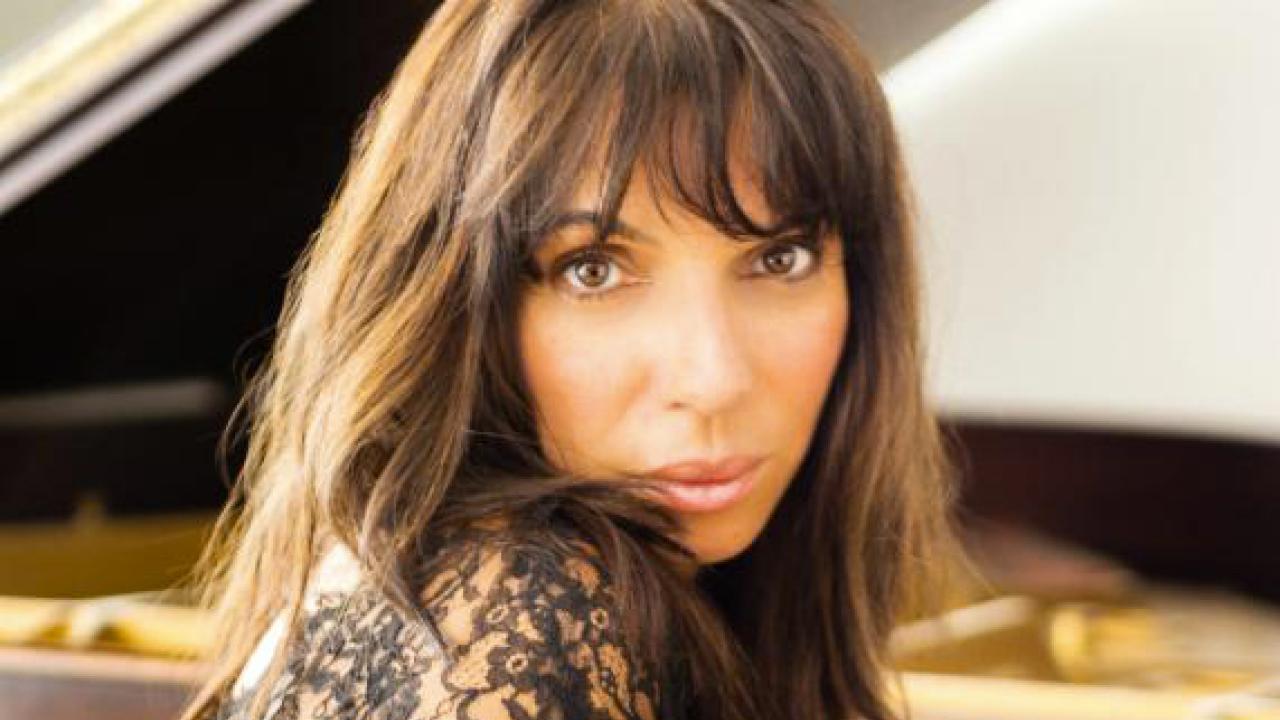 Photo: Lara Downes posed, on piano bench