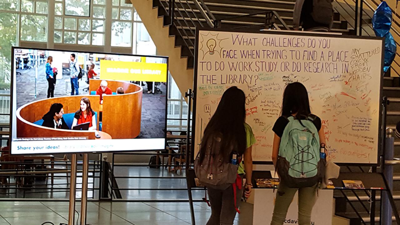 Students look at a white board asking about their space needs in the library