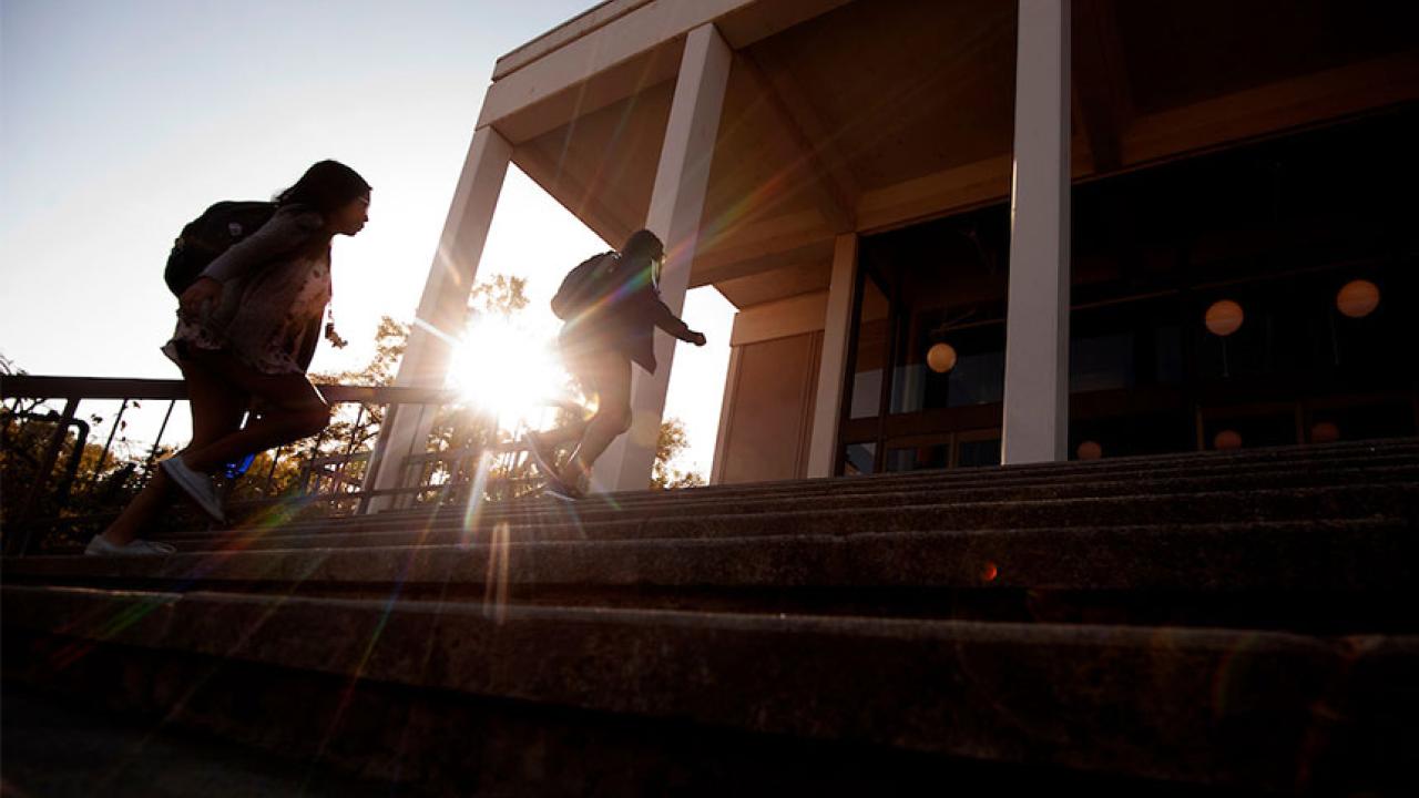 Two students climb the stairs in front of Rock Hall