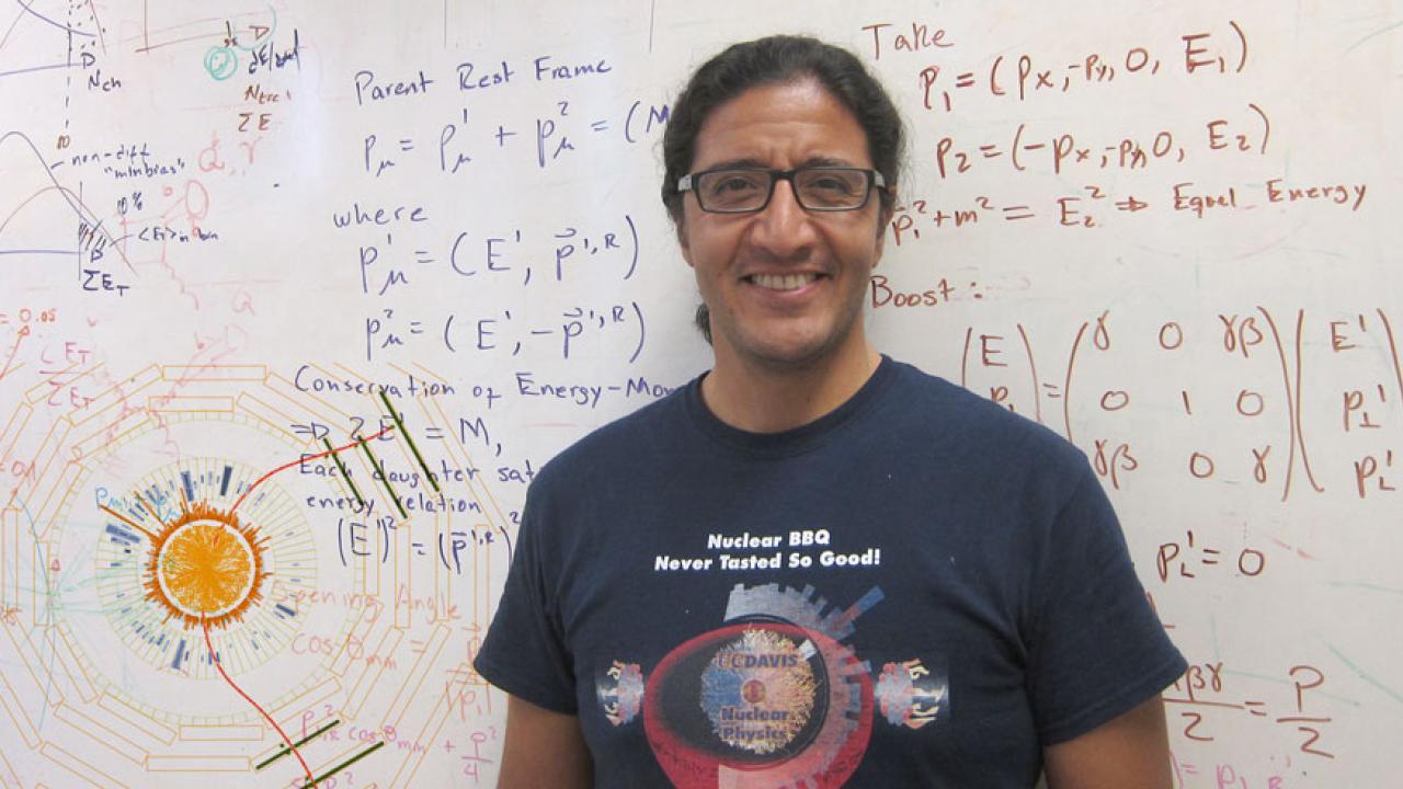 Man stands in front of whiteboard filled with calculations.