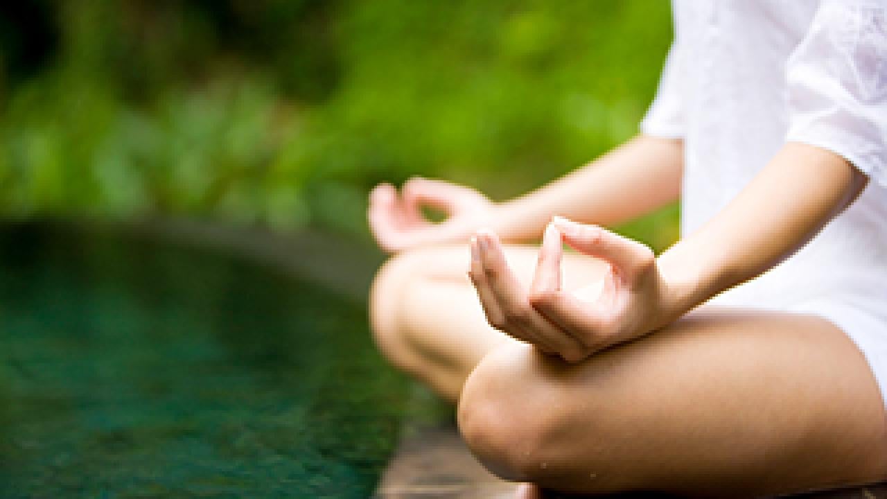 Woman in peaceful meditation pose crossing legs and with thumbs touching forefinger
