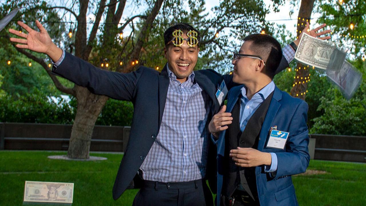 Two male students, one with arms extended in celebration