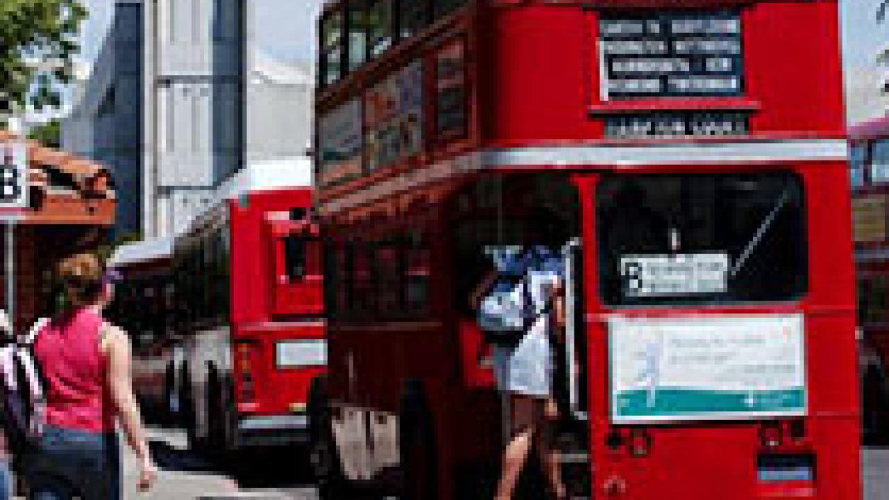photo: woman walking toward double-decker bus