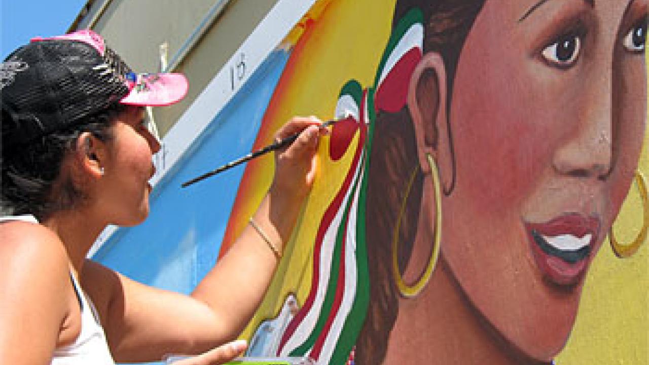 Photo: Maria Alvarado painting on a wall