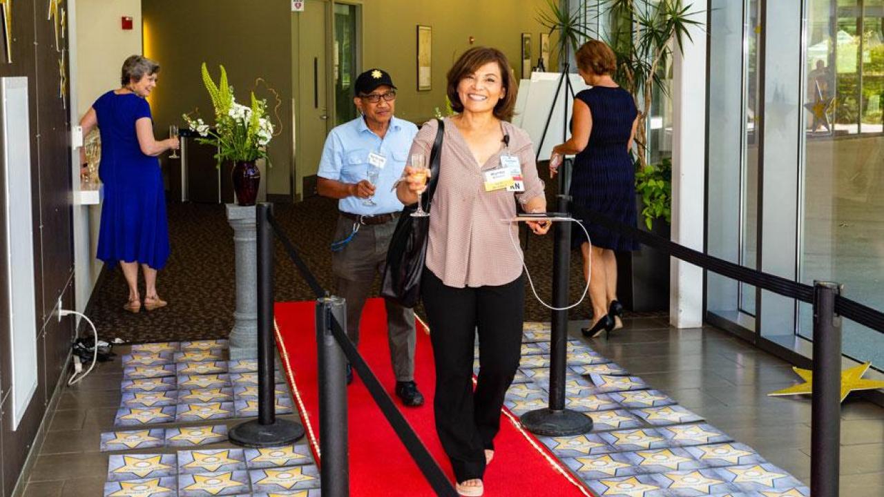 A woman walks along red carpet entry.