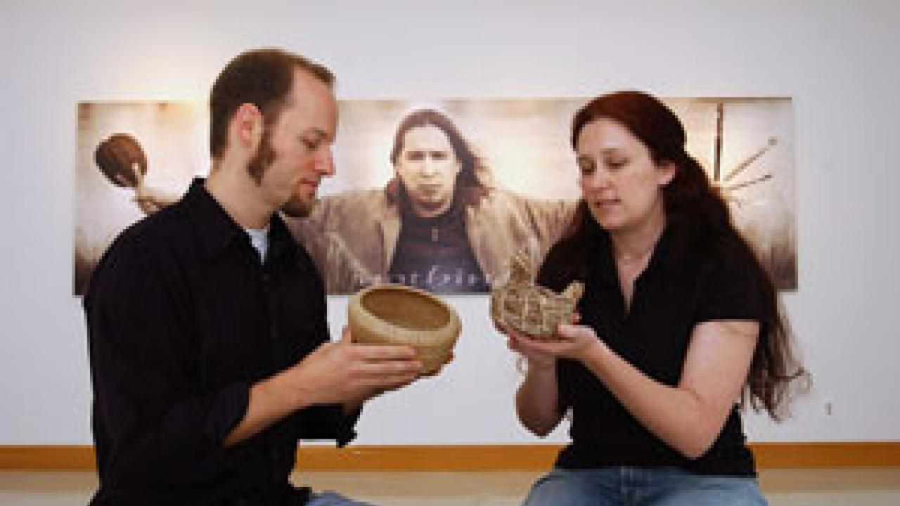 A photography exhibit by Shelley Niro provides the backdrop as 
Native American studies graduate students Michael Grofe and Lisa Woodard examine pine needle and sage baskets, respectively, in Carl Gorman Museum. The students say they are excite