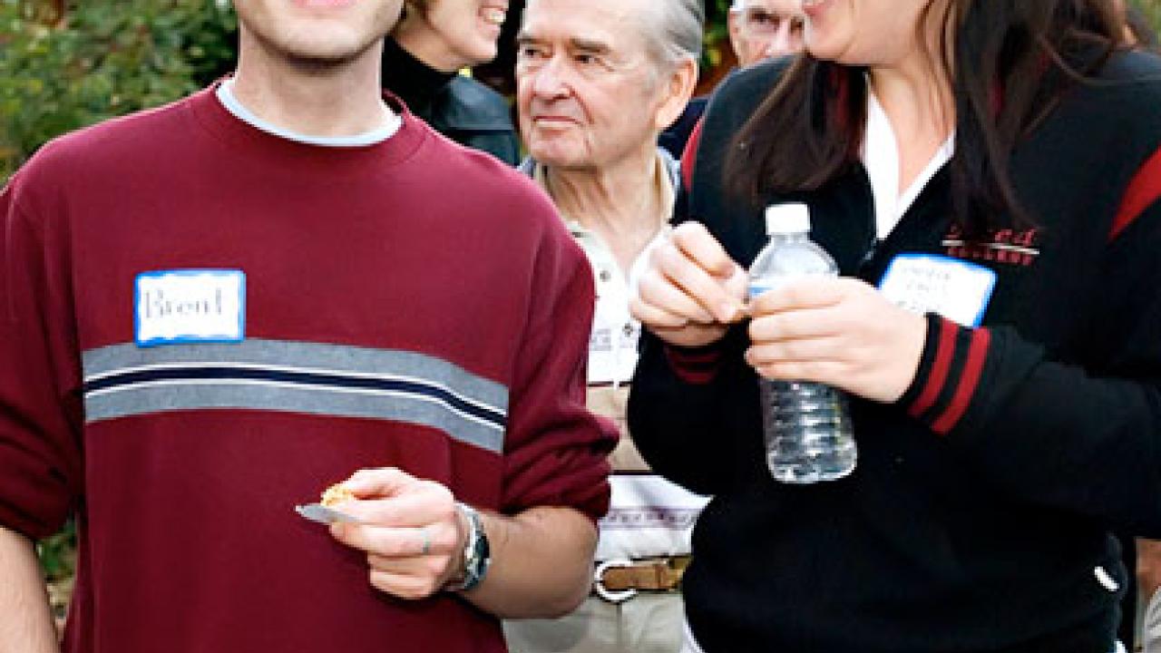 Photo: Group of people: guy looking at camera, woman laughing, looking at him, three older people behind