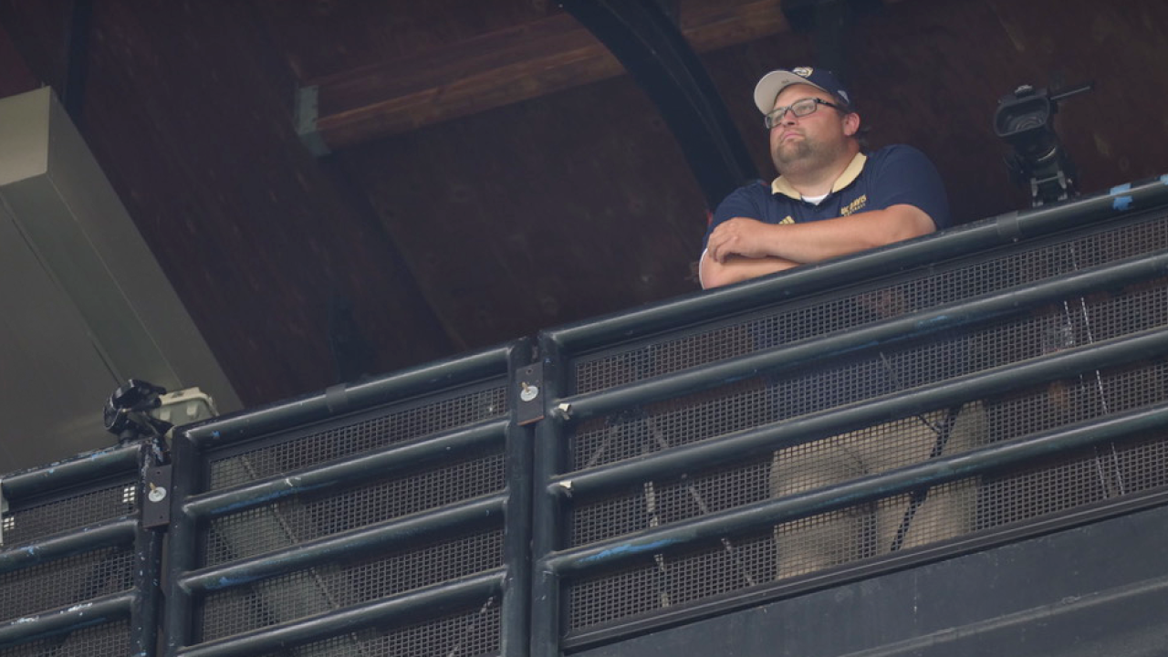 Tim Ornelas high above in media box, next to video camera