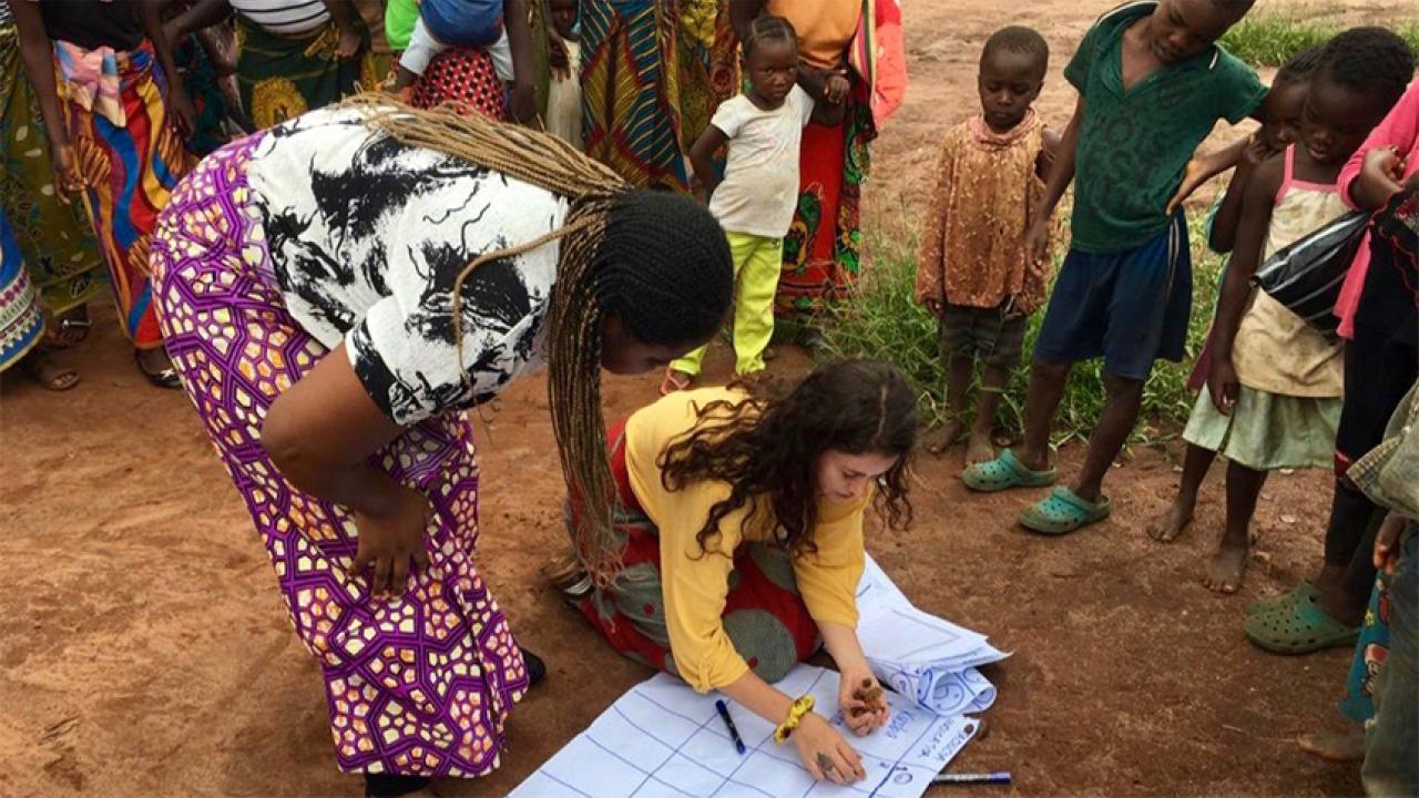 Woman kneels surrounded by children