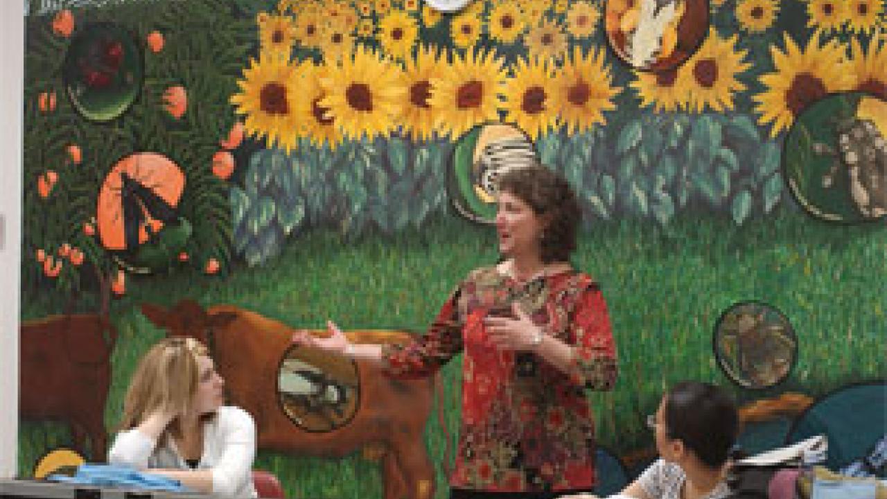 Against the backdrop of a mural painted last year, Diane Ullman teaches the freshman seminar Scientific Illustration in Public Murals, as students Madeline Osborn, left, and Karen Tam look on.   