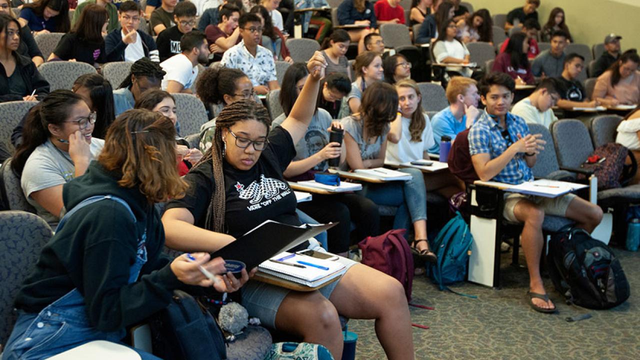 Student with hand raised in lecture
