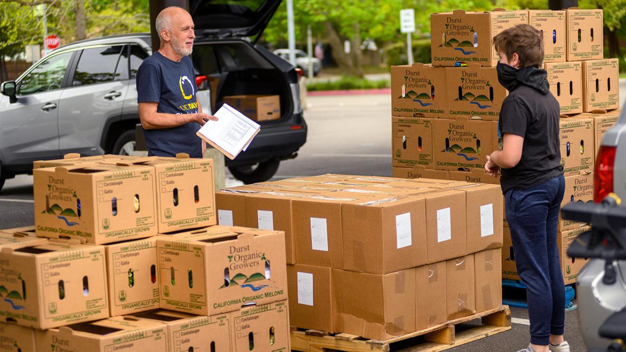 Robb Davis stands near boxes of food and a volunteer.