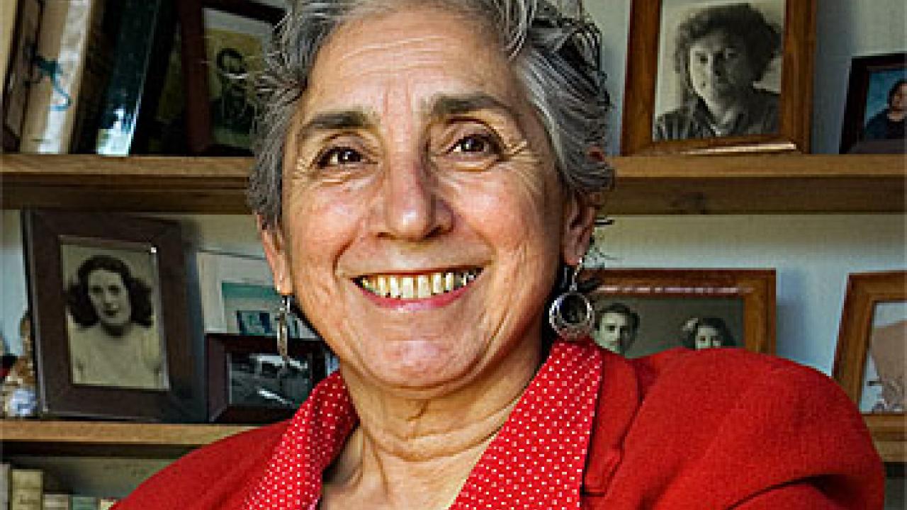 Photo: Brenda Deen Schildgen with photographs on shelves behind her.