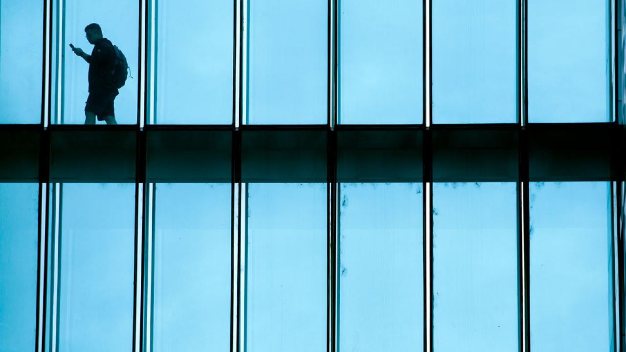 Unidentified person walks across glassed-in walkway.