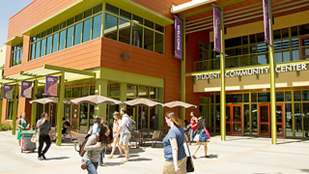 Outside of a two story building with sgn that says Student Community Center and several students walking in front
