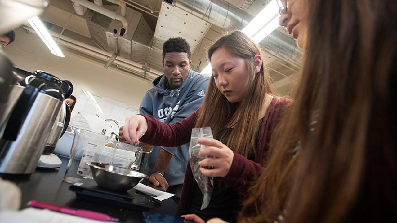 Three students in a lab working on coffee making