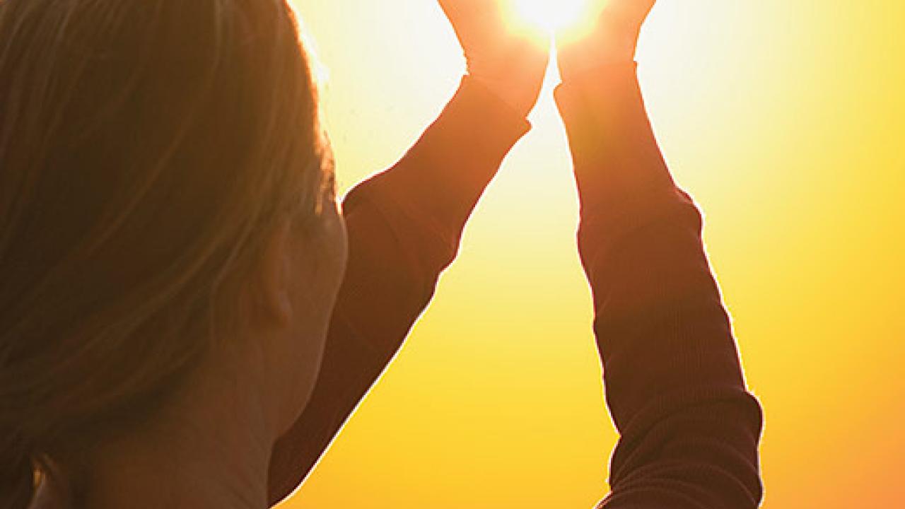 Woman cupping hands around the sun's image