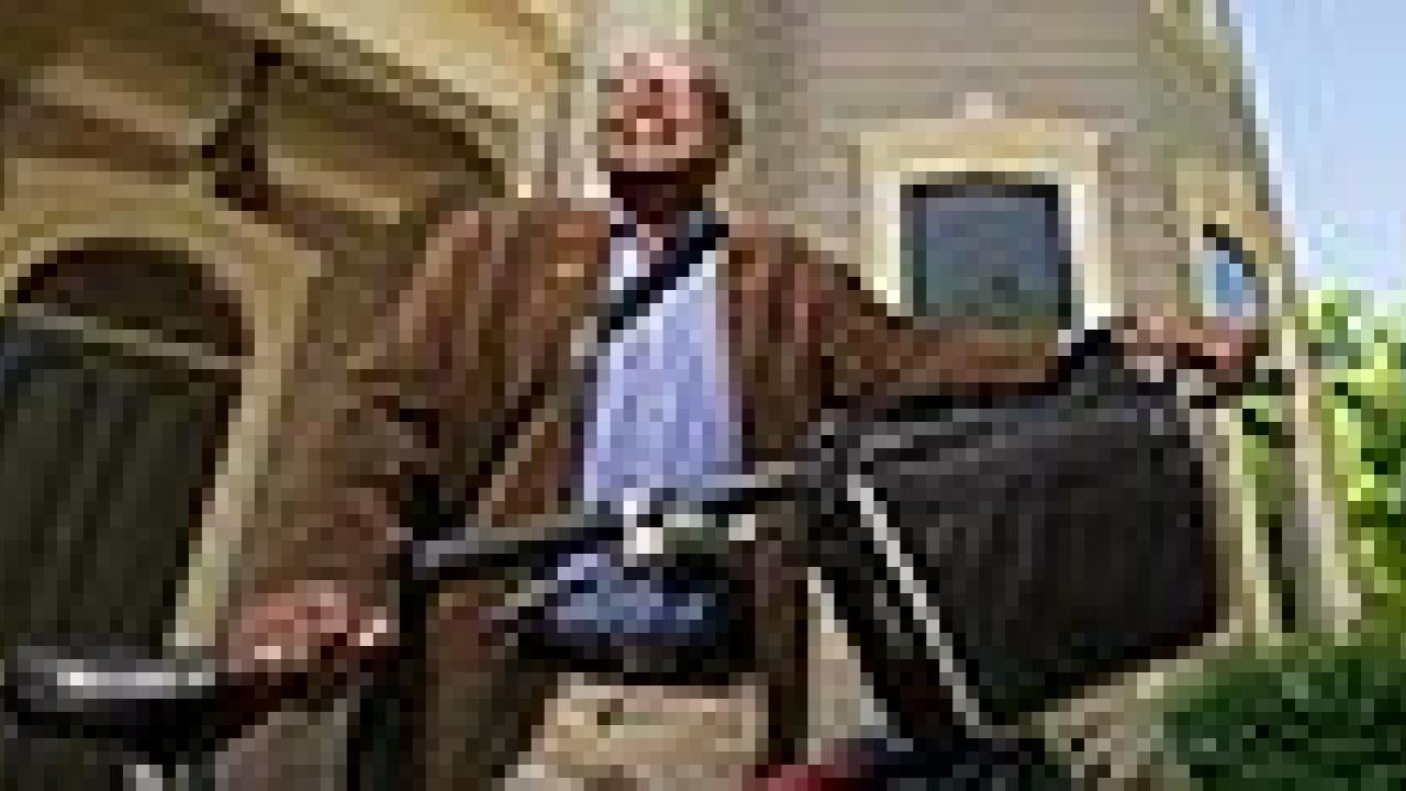 Clarence Walker standing holding his bike in front of a Victorian home