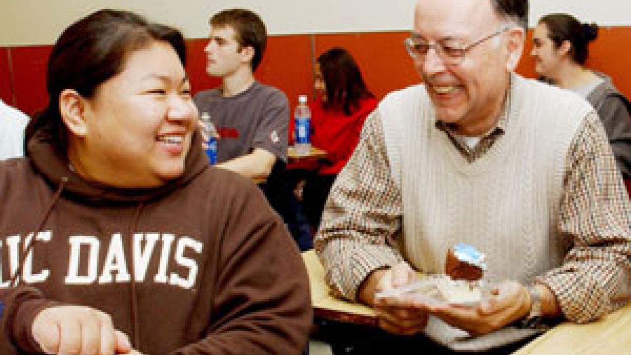 Francisco Samaniego enjoys a celebratory piece of cake while chatting with student Khemera Saman.