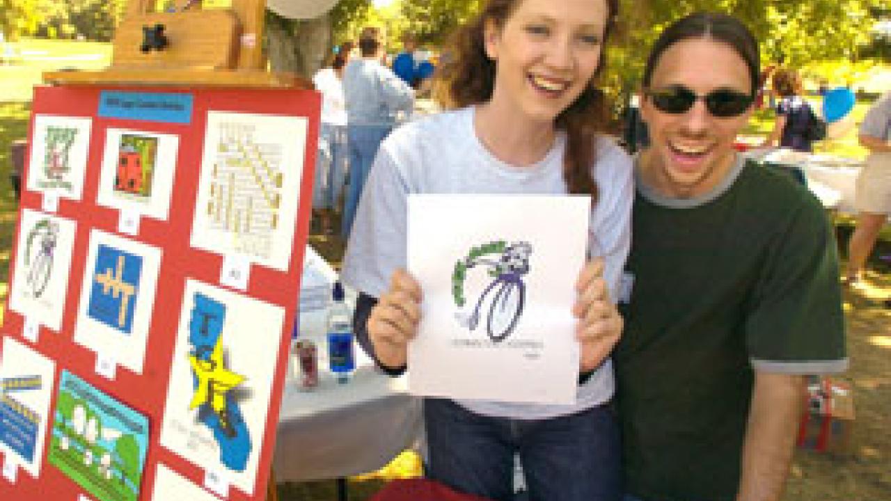 Bethany Daniels and Richard Sutherland of communication resources show off the winning TGFS logo design for next year, created by Holly Guenther of insurance services.