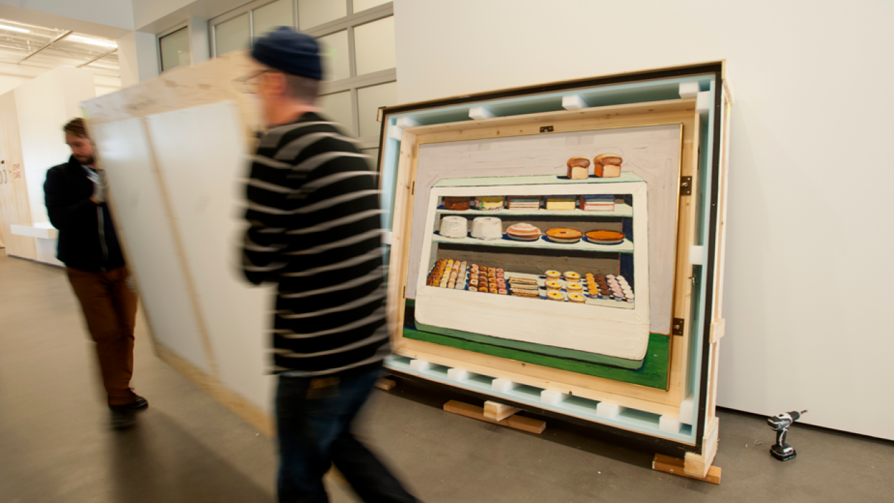 Museum workers remove crate from top of crate holding a Wayne Thiebaud painting.