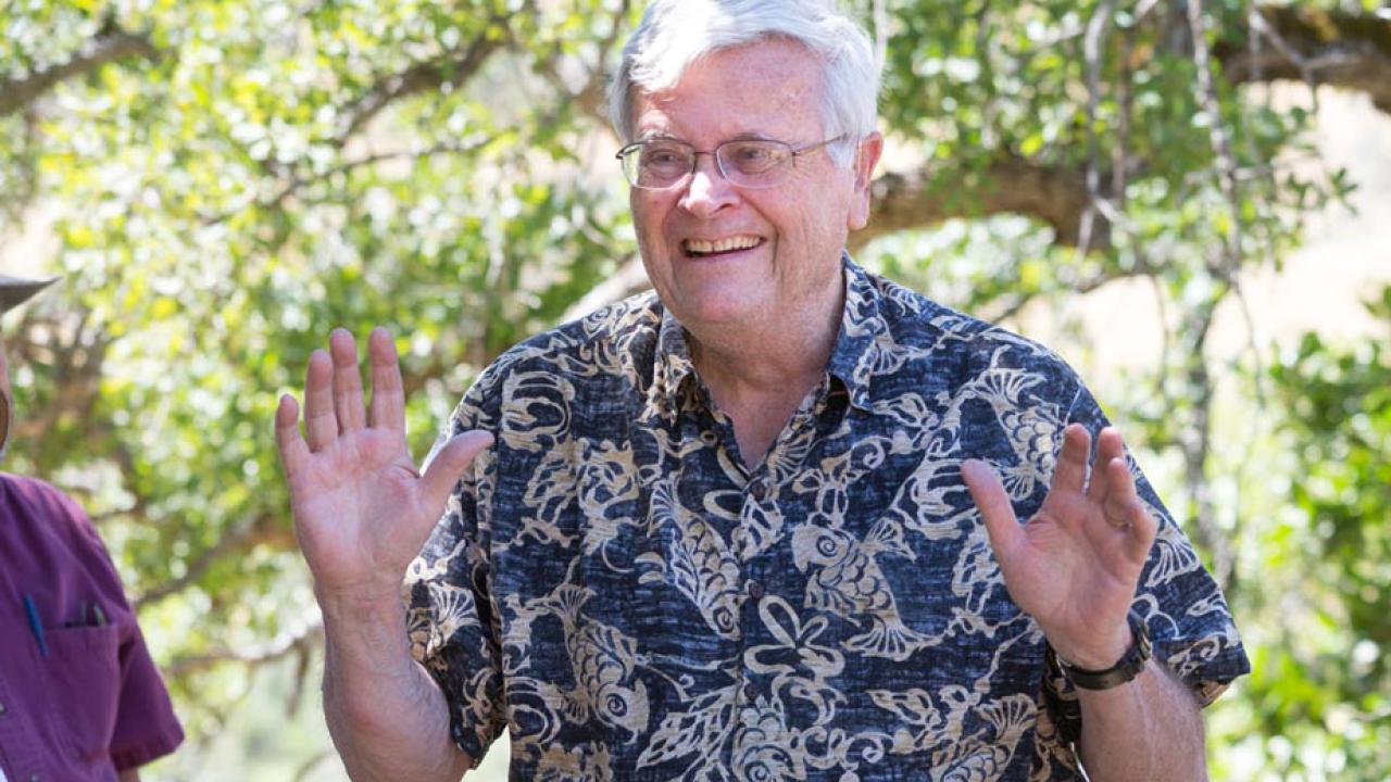 Tom Cahill, smiling, throwing hands up, at riparian preserve donation, May 2017.