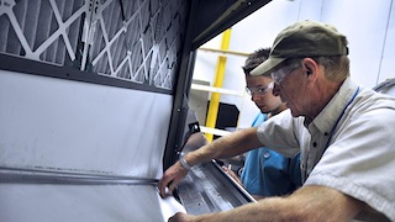Two men inspecting an air conditioner