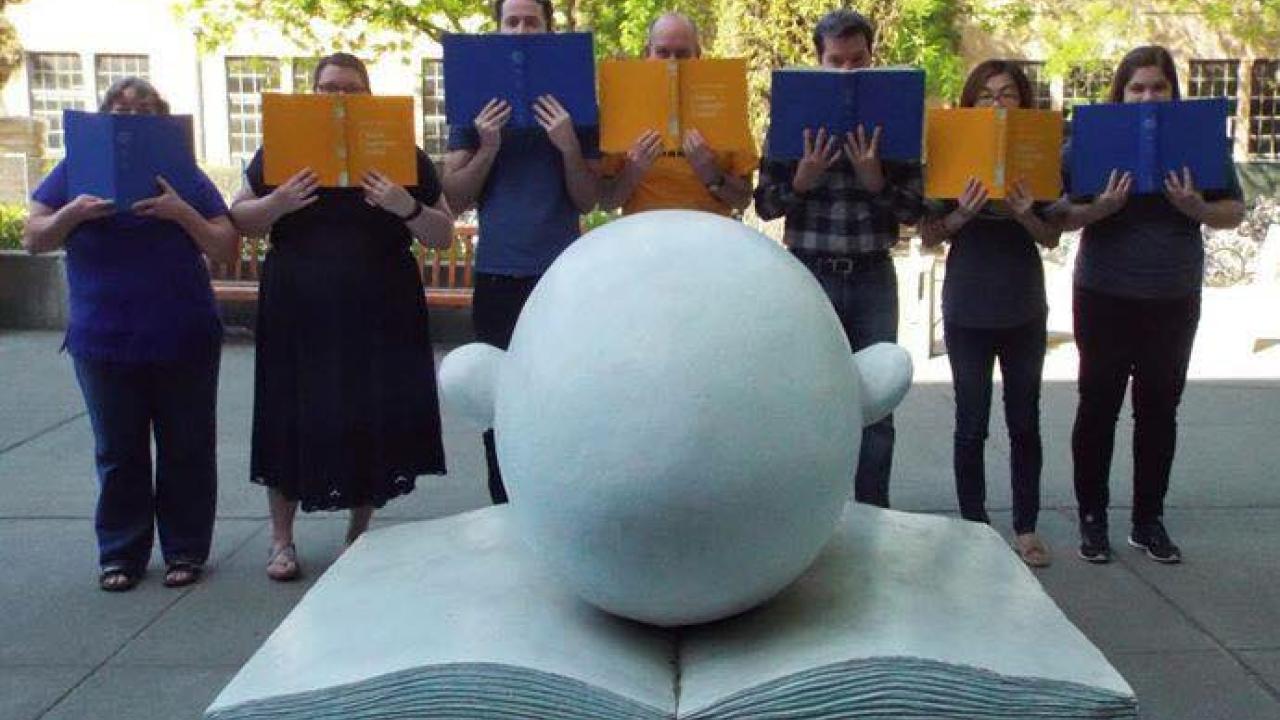 Staff members pose with blue and gold books.