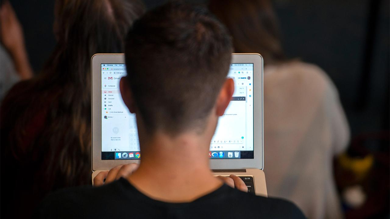 A student types an email on a laptop computer.