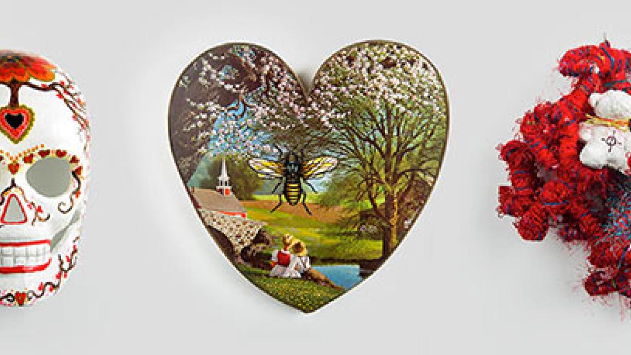 a decorated skeleton mask, a heart-shaped painting and a mixed-media piece shaped like a human heart organ with a teddy bear 