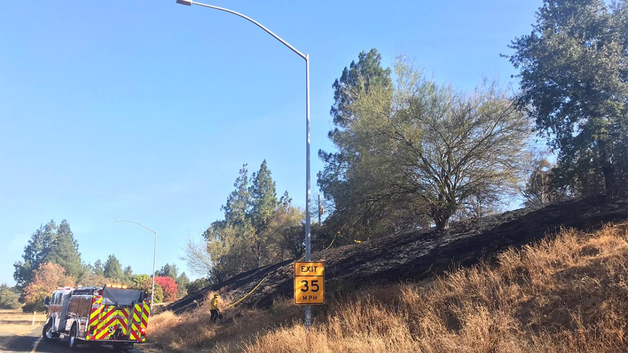 A fire truck next to a burned hillside.