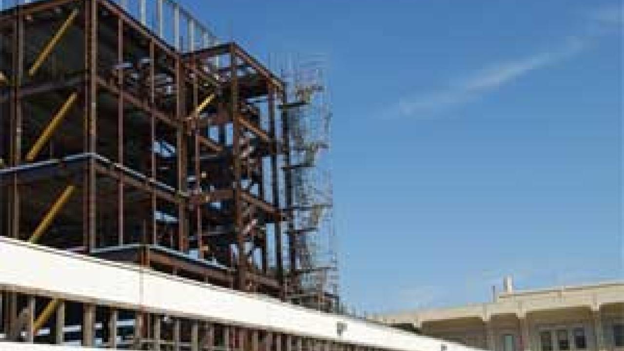 Photo: steel girders of a new building next to an existing two-story building
